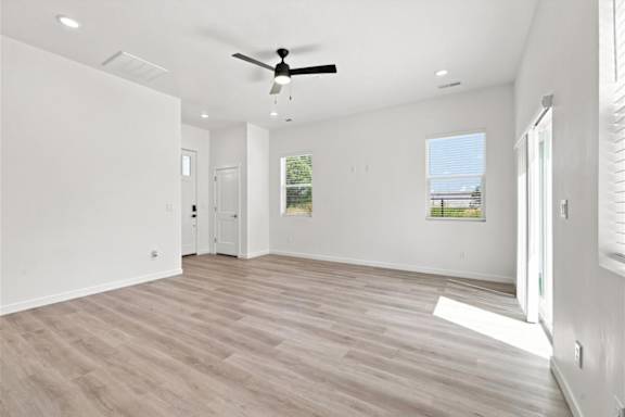 A spacious room with a ceiling fan and lighting fixtures.