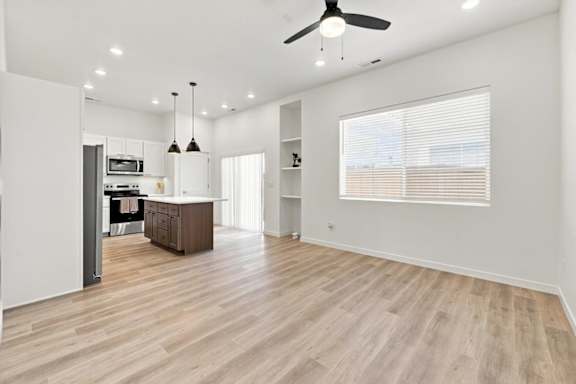 A spacious room with a wooden floor and a ceiling fan.