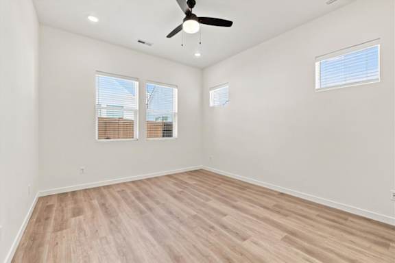 A room with a ceiling fan and wooden flooring.