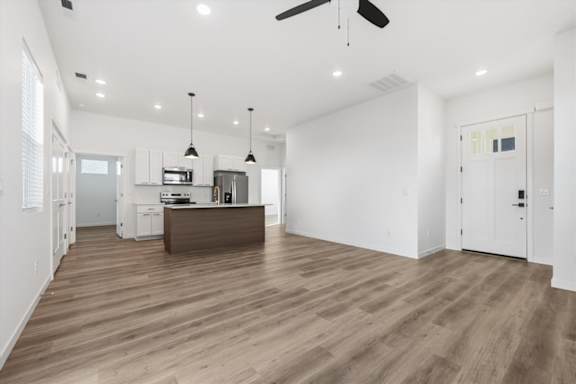 Living room with ceiling fan and kitchen with brown island at Alante Homes at Spring Run, Idaho, 83607