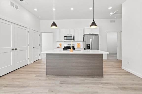 A modern kitchen with a central island and pendant lights.