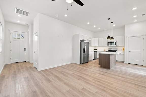 A kitchen with a refrigerator, microwave, and oven.