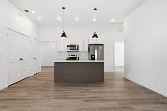 Bright kitchen with wooden island and pendant lights at Alante Homes at Spring Run, Caldwell, 83607