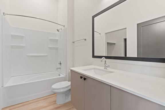 A white bathroom with a toilet, sink, and shower.