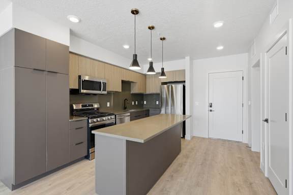 Modern kitchen with large island in the middle with pendant lights at Brickside Heights, Millcreek, UT
