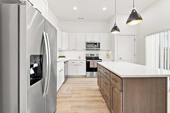 A modern kitchen with a stainless steel refrigerator and wooden cabinets.