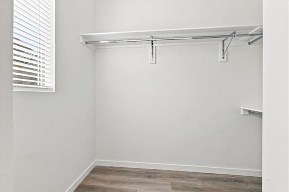 A white wall with a wooden floor and a white shelf.