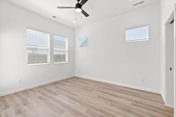 A room with a ceiling fan and two windows.