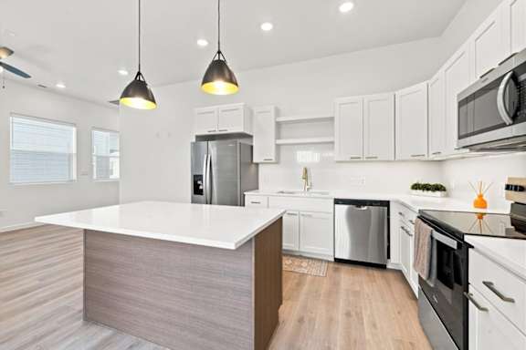 A modern kitchen with a white countertop and stainless steel appliances.