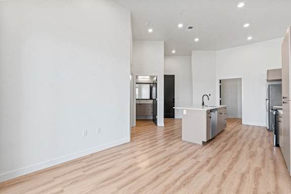 A kitchen area with a refrigerator, sink, and cabinets.