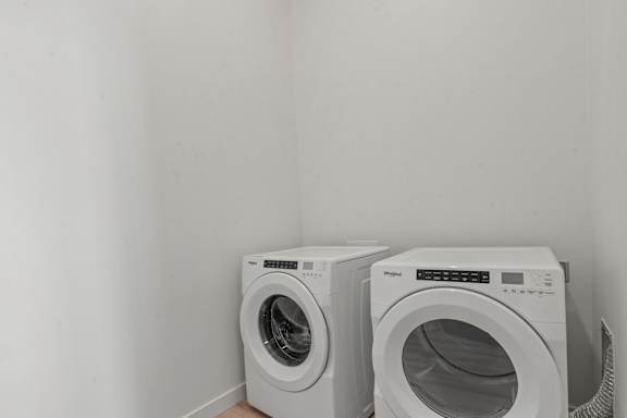 Two white front load washing machines in a laundry room.