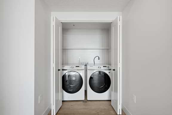 White laundry room with two front loading washing machines at Brickside Heights, Millcreek