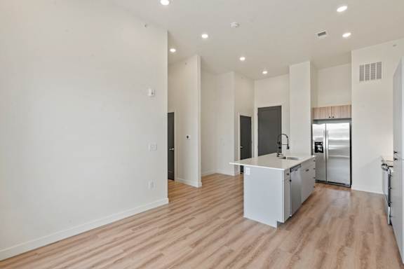 A kitchen with a refrigerator, sink, and cabinets.