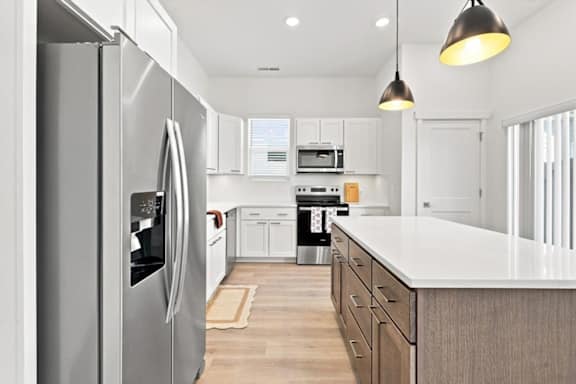 A modern kitchen with a refrigerator on the left and a microwave above the stove.