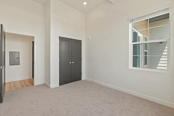 A room with a black door and a window with blinds.