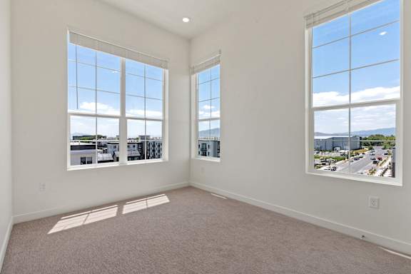 A large empty room with two windows overlooking a cityscape.