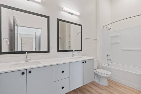 A white bathroom with a sink, mirror, toilet, and bathtub.