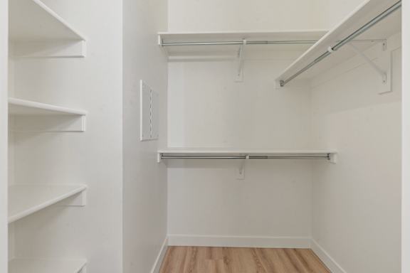 A white closet with shelves and a clothes rack.