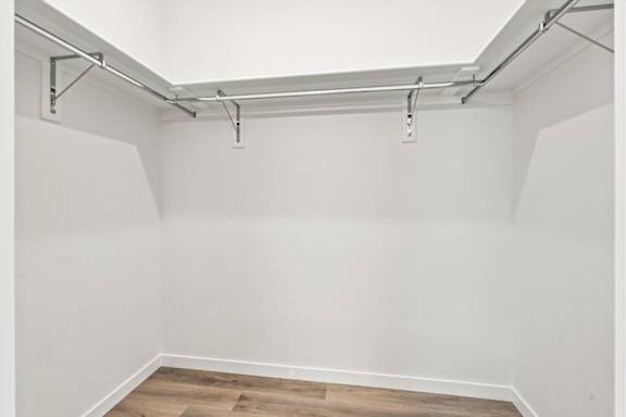 A white wall with a wooden floor and a metal pipe running along the top.