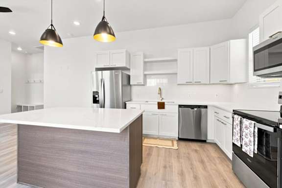 A modern kitchen with a white island and stainless steel appliances.