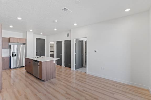 A kitchen with a refrigerator, sink, and cabinets.