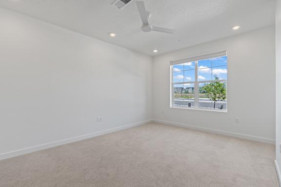 A room with a window showing a view of a street and trees.