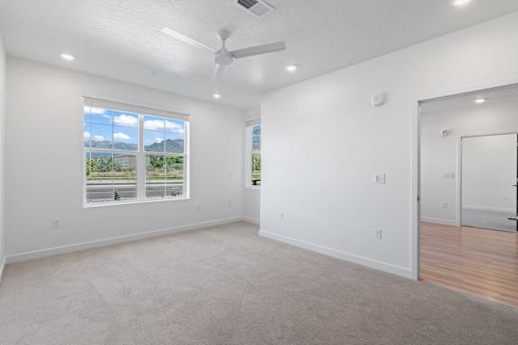 A spacious room with a ceiling fan and a large window overlooking a highway.
