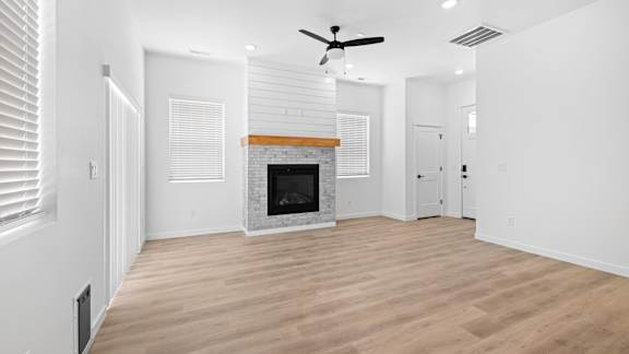 A spacious living room with a fireplace and a ceiling fan.at Alante Homes at Spring Run, Caldwell, 83607