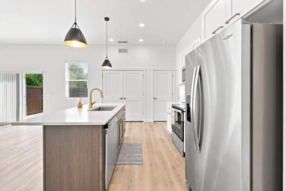 A modern kitchen with a large refrigerator and wooden cabinets.