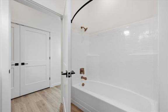 White bathroom with tub and glass door at Alante Homes at Spring Run, Caldwell, ID, 83607
