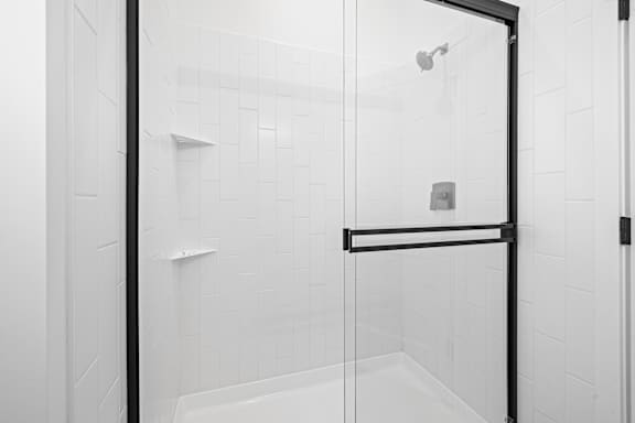 A white tiled bathroom with a glass shower door.at Alante Homes at Spring Run, Idaho