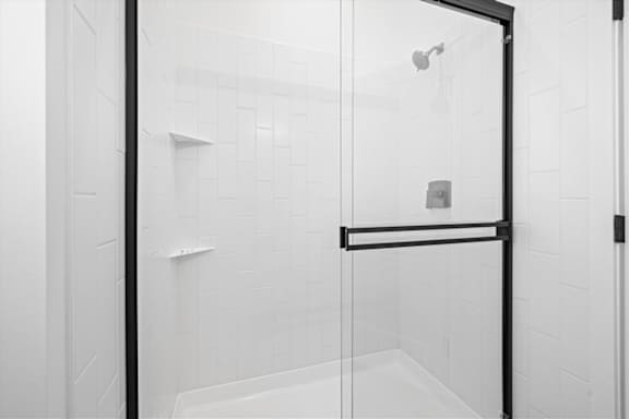A white tiled shower with a black frame.