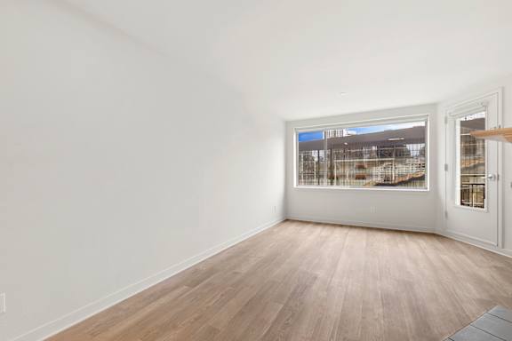 Empty room with wooden floor and white walls at AVIA on Pike Street, Seattle, Washington