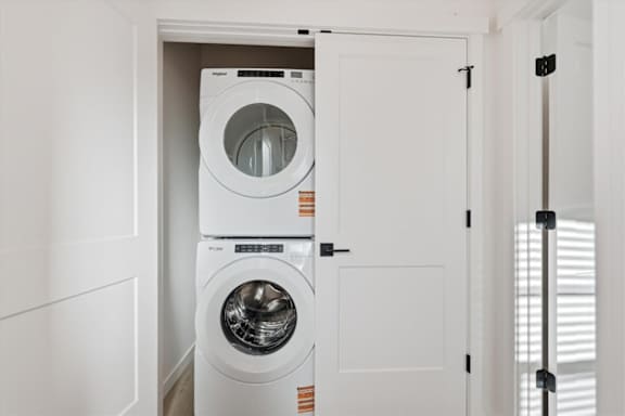 Stacked washing machine and dryer in small laundry room at Alante Homes at Spring Run, Caldwell