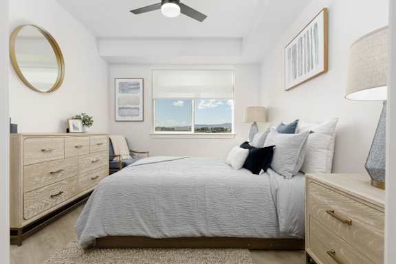 A bedroom with a bed, dresser, and window. at The Vue At Desert Color, St. George, UT