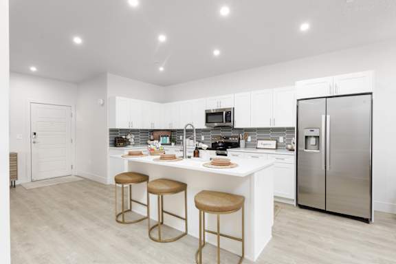 A modern kitchen with a white island and stools. at The Vue At Desert Color, St. George