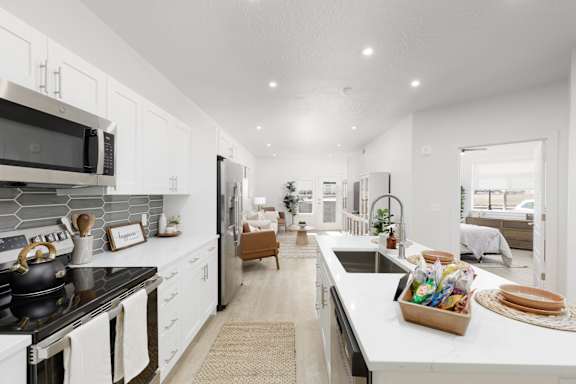A modern kitchen with white cabinets and a black stove top. at The Vue At Desert Color, St. George, UT, 84790