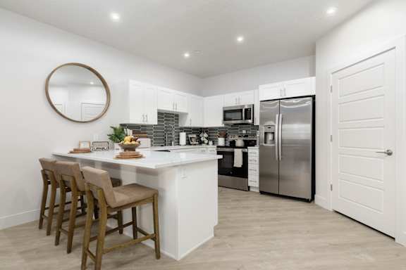 A kitchen with a white island and stainless steel appliances. at The Vue At Desert Color, St. George, UT