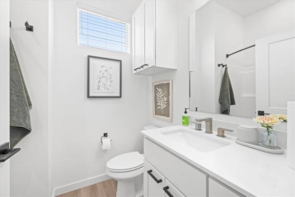 A white bathroom with a toilet, sink, and mirror.