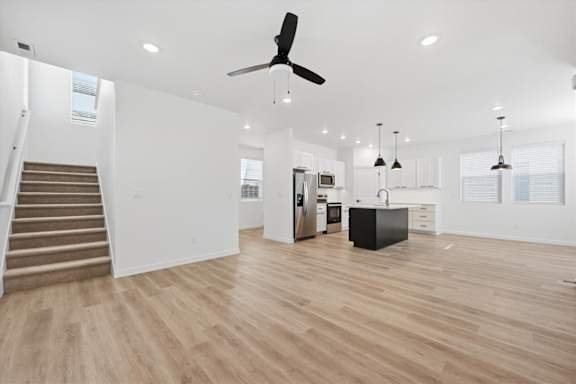Spacious kitchen and living room with wooden flooring and a staircase at Alante Homes at Spring Run, Caldwell, 83607