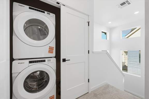 Stacked white washing machine and dryer in laundry room at Alante Homes at Spring Run, Caldwell, 83607