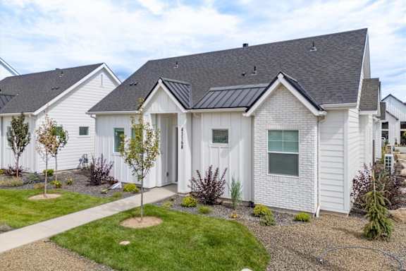 A white house with a black roof and a small garden in front. at Alante Homes at Spring Run, Caldwell