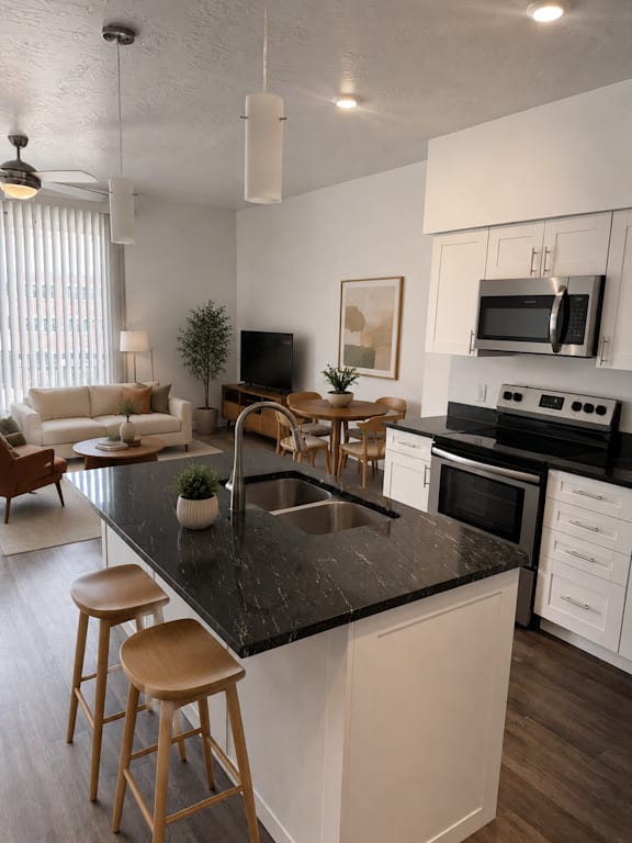 A modern kitchen with a black countertop and white cabinets.