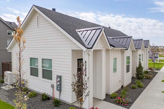 A white house with a grey roof and a grey gravel area in front.