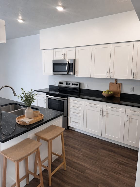 A kitchen with white cabinets and black countertops.