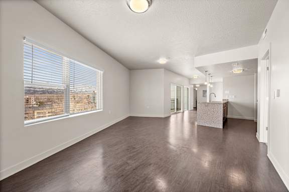 A large empty room with wooden floors and a view of a construction site through the window at Wilmington Flats Apartments, Utah, 84106