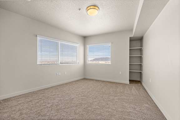 A room with a carpeted floor and two windows. at Wilmington Flats Apartments, Salt Lake City