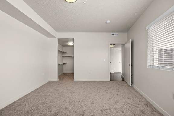 A spacious room with a carpeted floor and a window with blinds. at Wilmington Flats Apartments, Salt Lake City, Utah