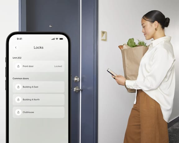 A woman is looking at her phone which displays a lock screen.