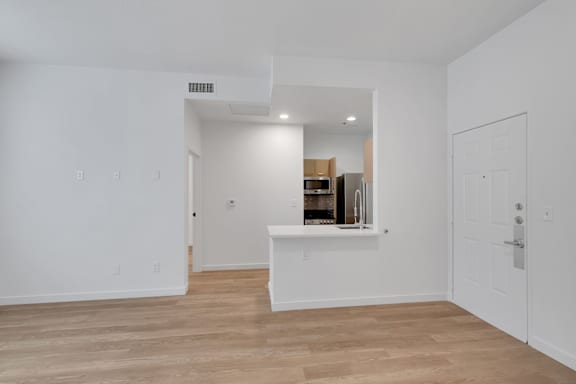 A white room with a wooden floor and a white counter.